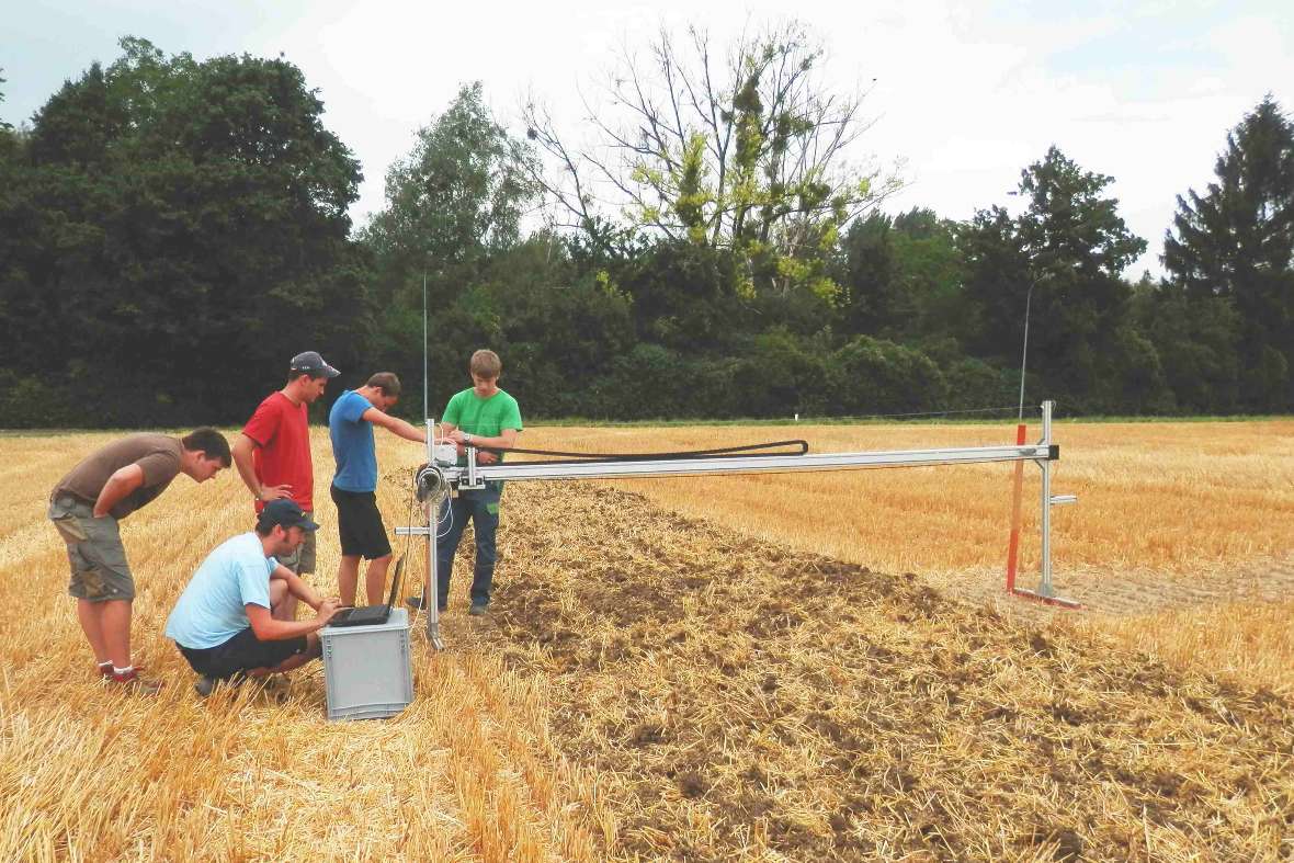 Some people on the test field with a measuring device (Soil tillage and sowing technology)