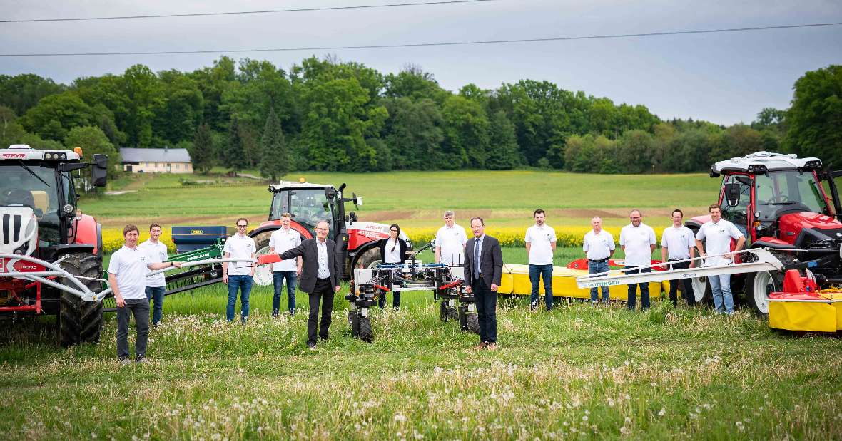 Landmaschinen auf der Wiese mit Personen